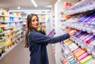 Winkelmedewerker bij de Albert Heijn legt spullen in het schap