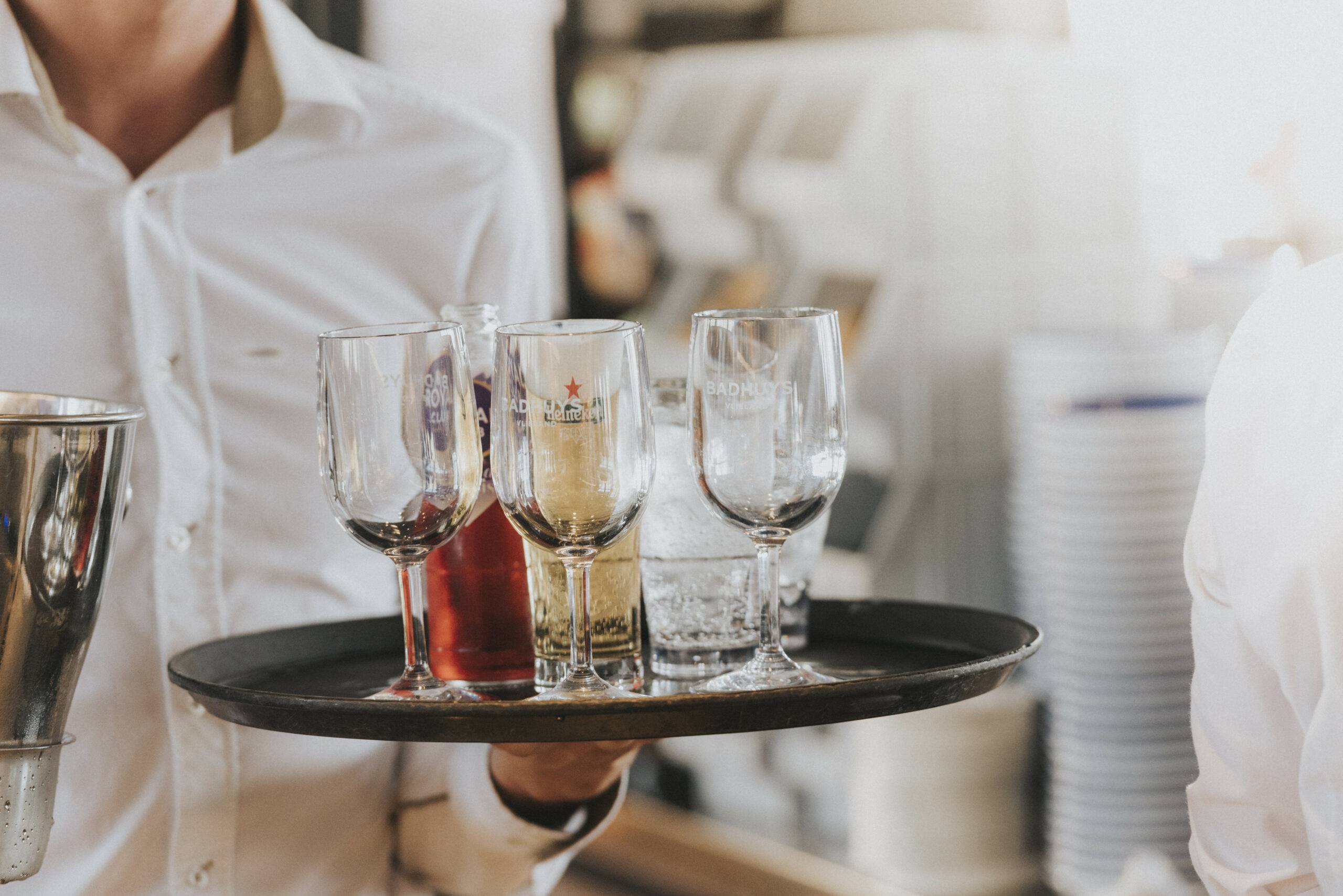 Bedieningsmedewerker houdt dienblad met glazen vast
