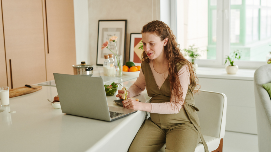 Vrouw zit aan de keuken met een laptop