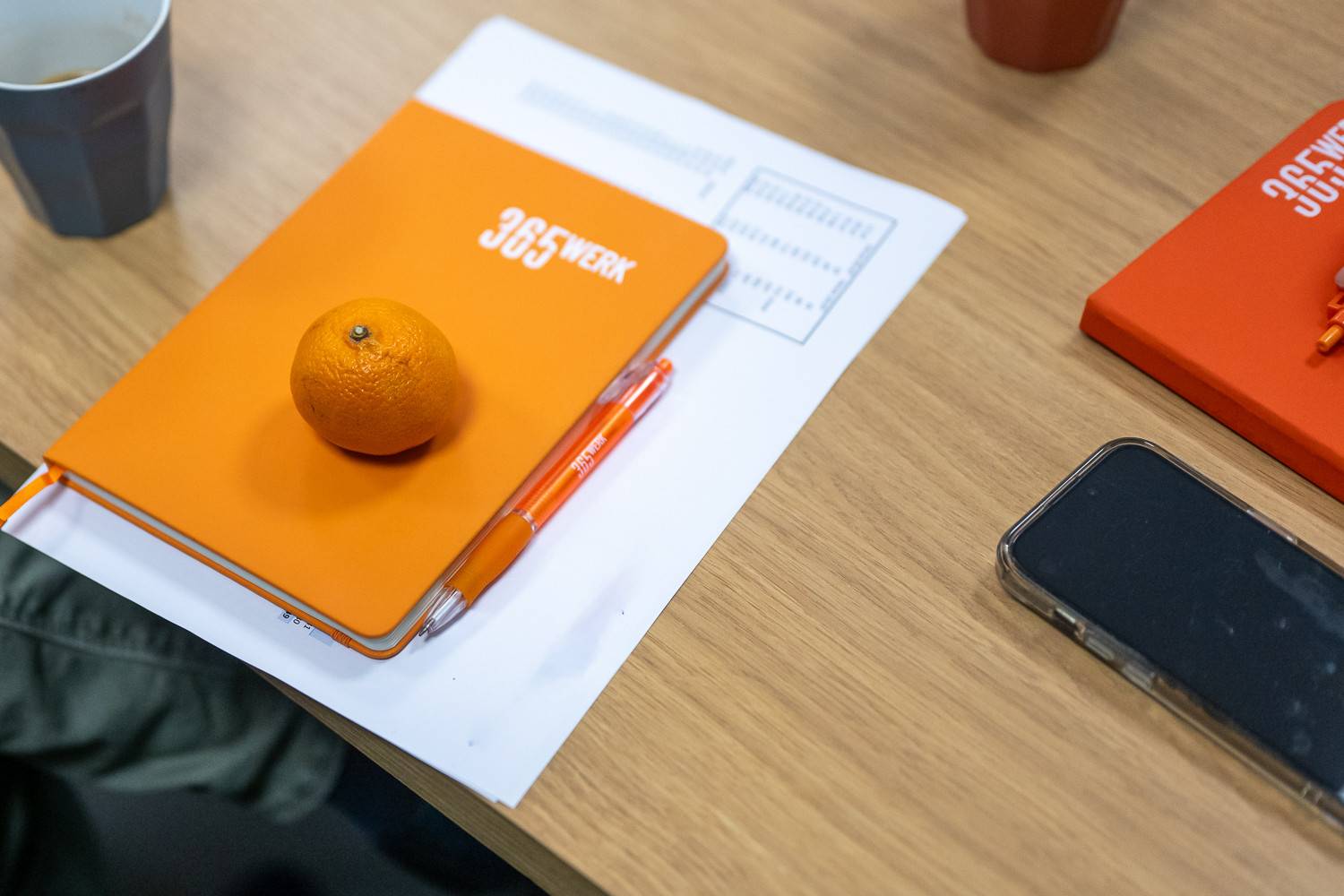 Tafel met notitieboekje van 365werk met een mandarijn erop