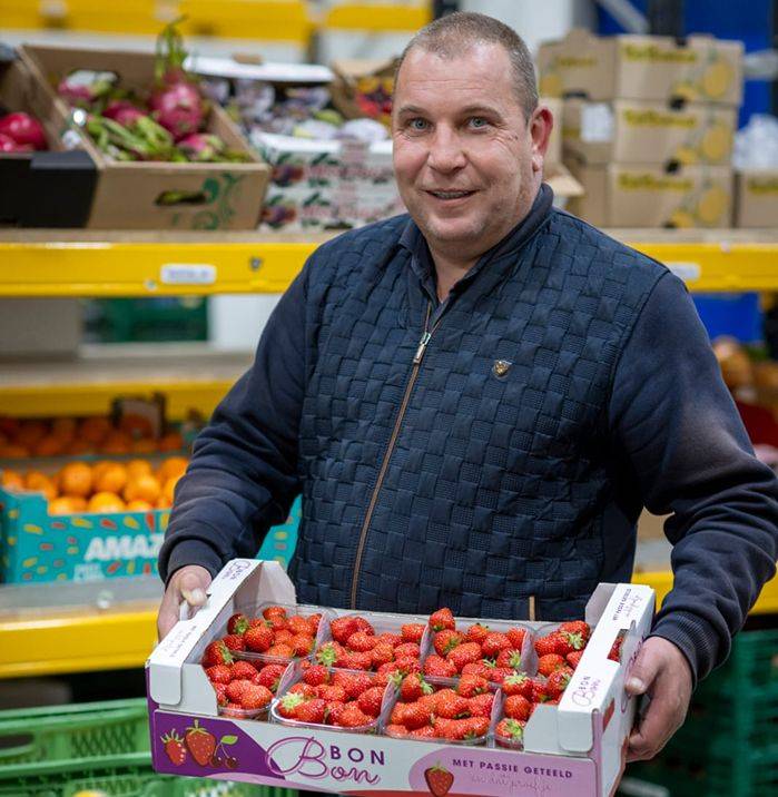 Actifood medewerker houdt bak met aardbeien vast