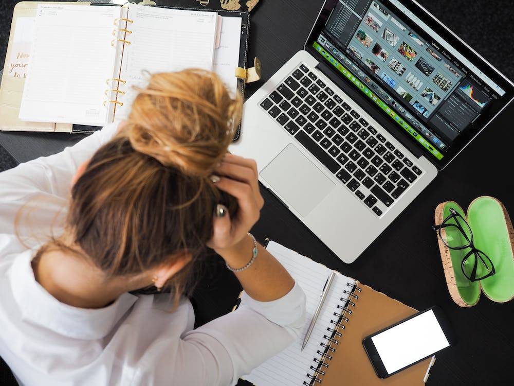 Vrouw met handen in het haar achter de laptop