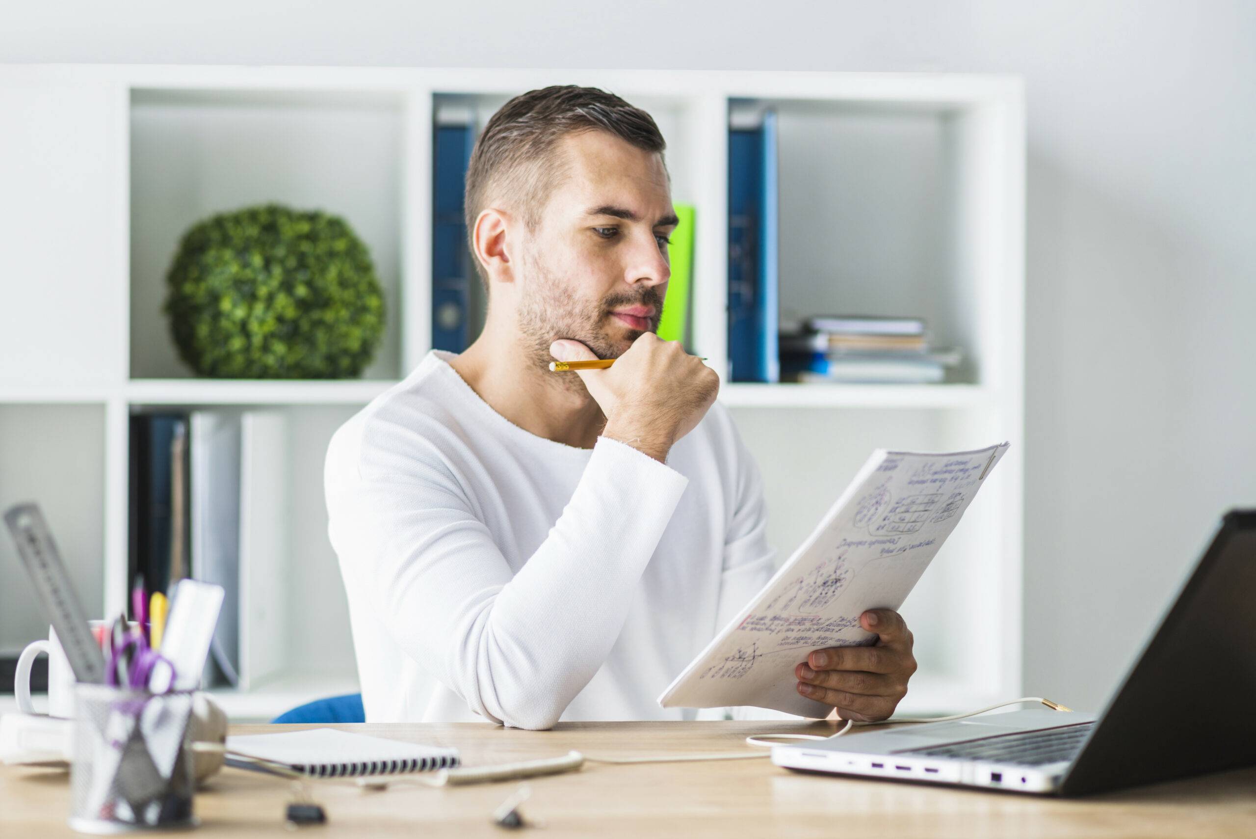 Man zit achter bureau en heeft schrift in zijn handen denkt na