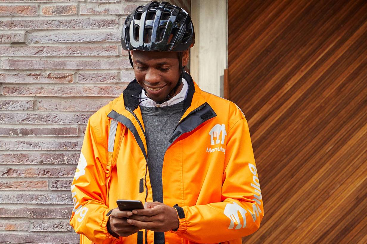 Fietsbezorger van Thuisbezorgd met helm op checkt telefoon