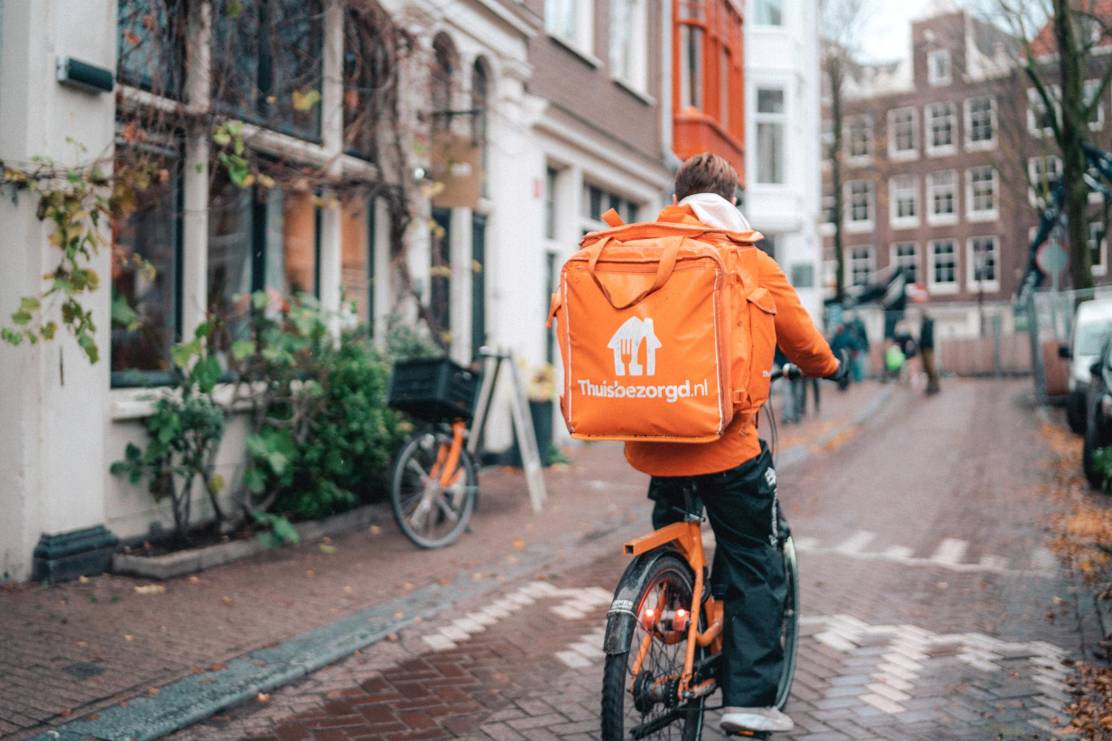 Fietsbezorger van Thuisbezorgd fiets door straat