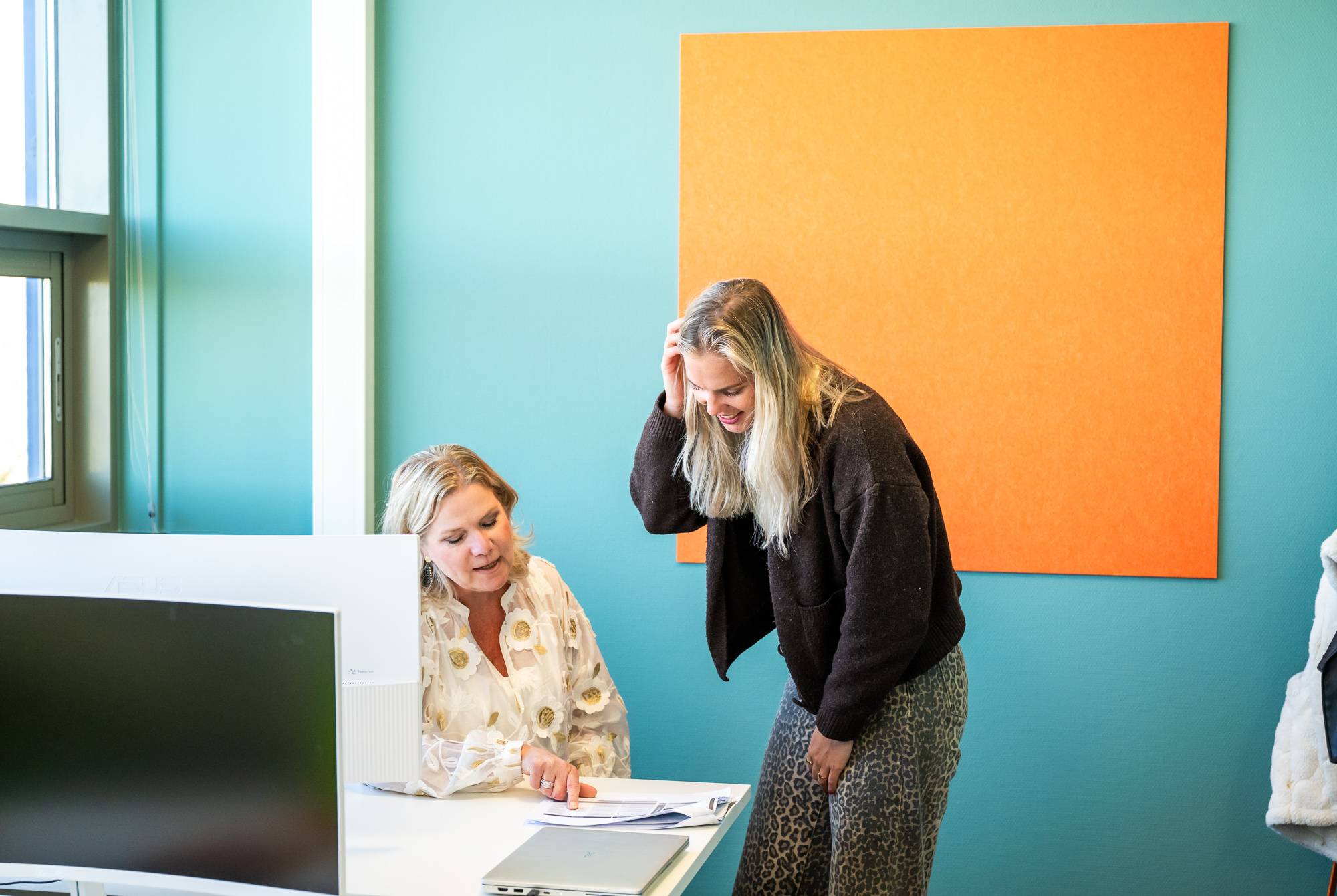 Twee collega's hebben een gesprek bij het bureau en bekijken document