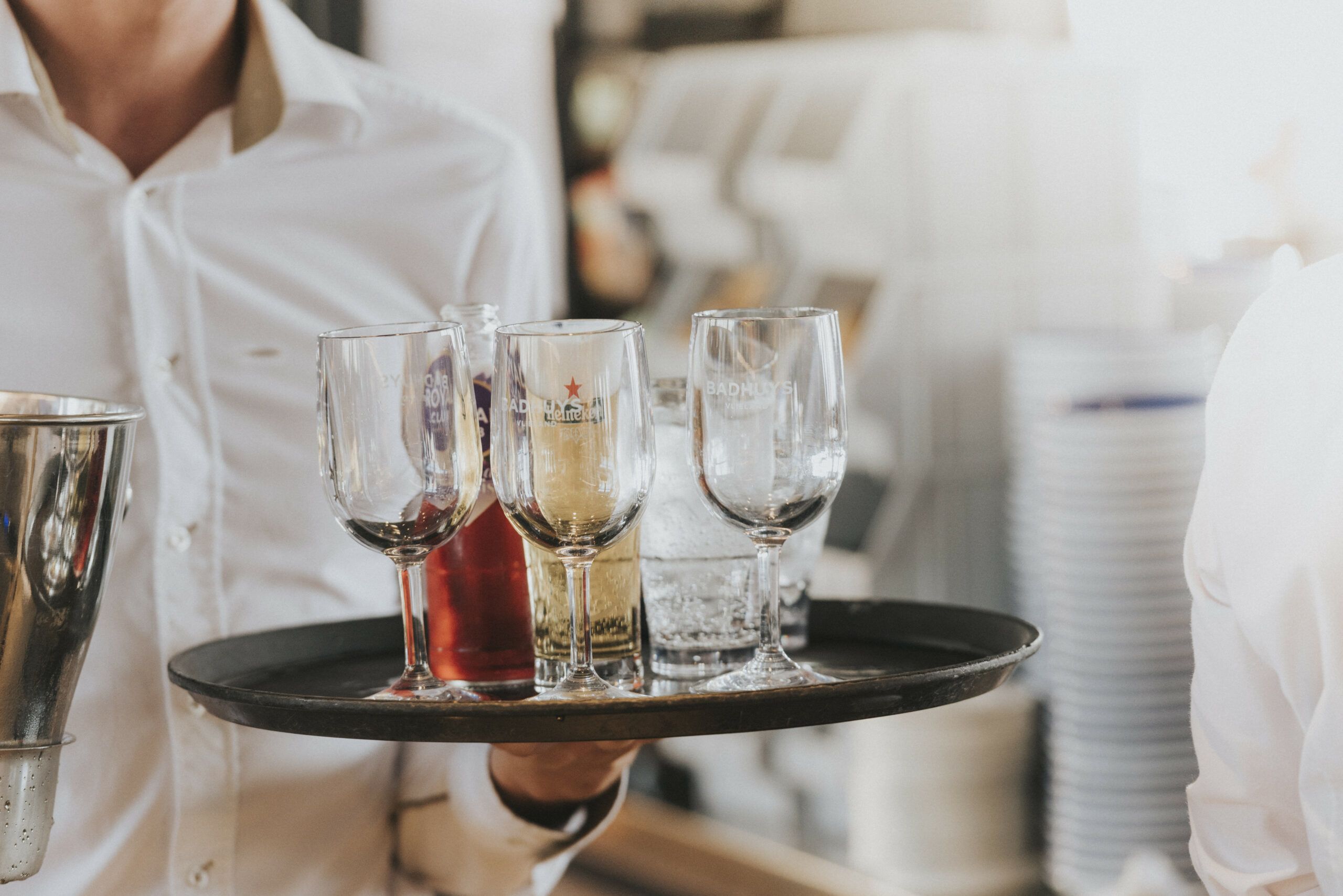 Bedieningsmedewerker houdt dienblad met glazen vast