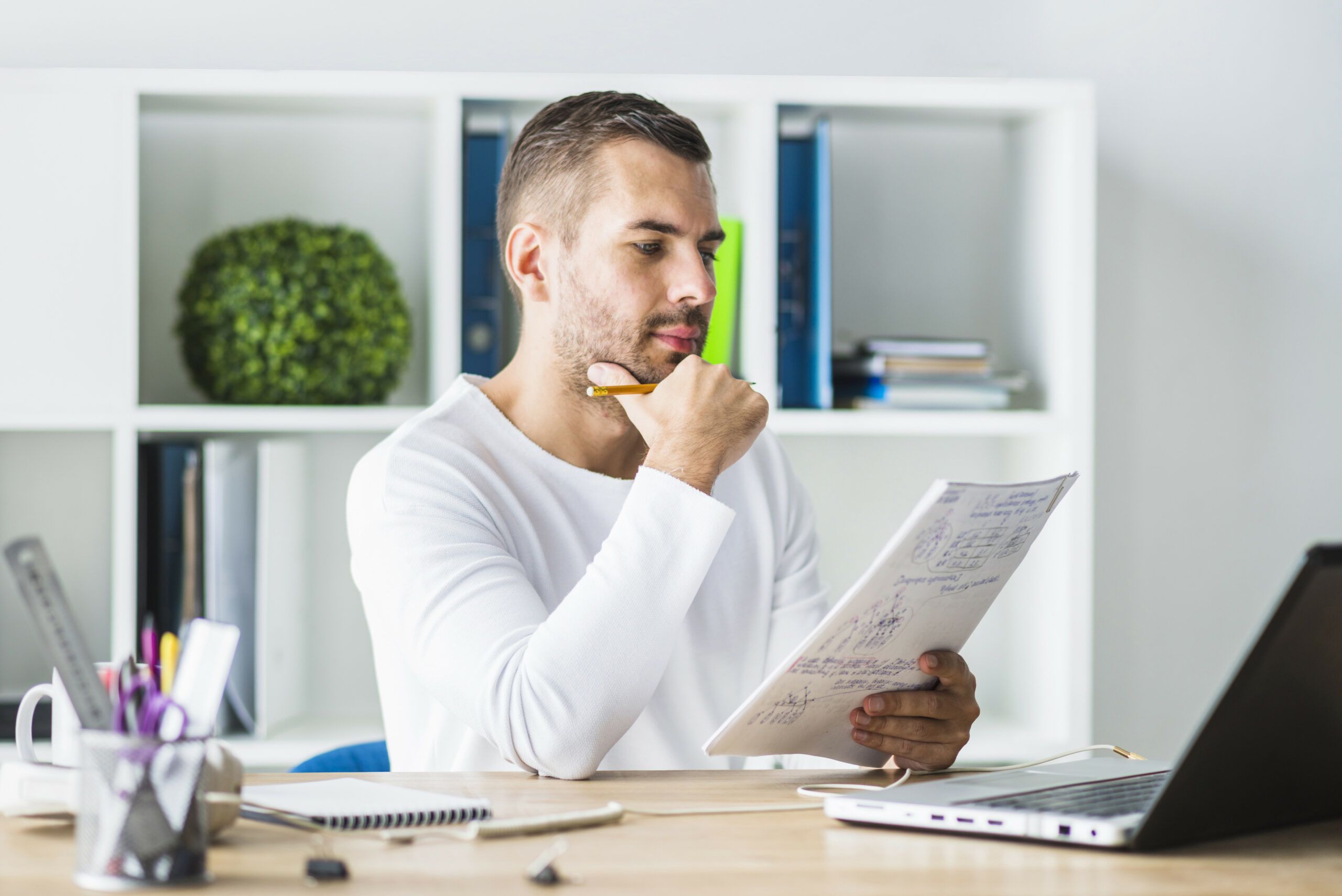Man zit achter bureau en heeft schrift in zijn handen denkt na